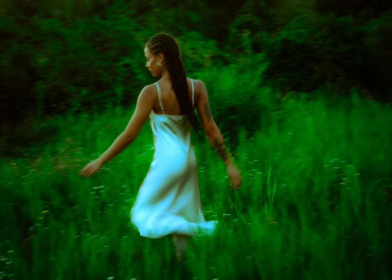 Woman of colour running through the grass in twilight