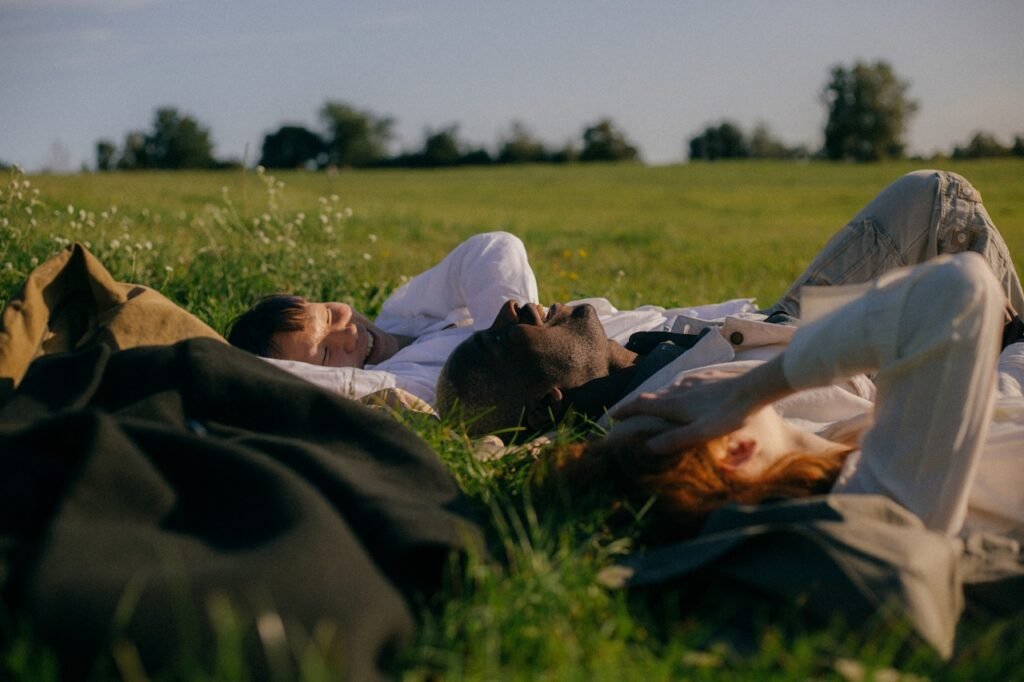 A group of friends laying together on a grassy field