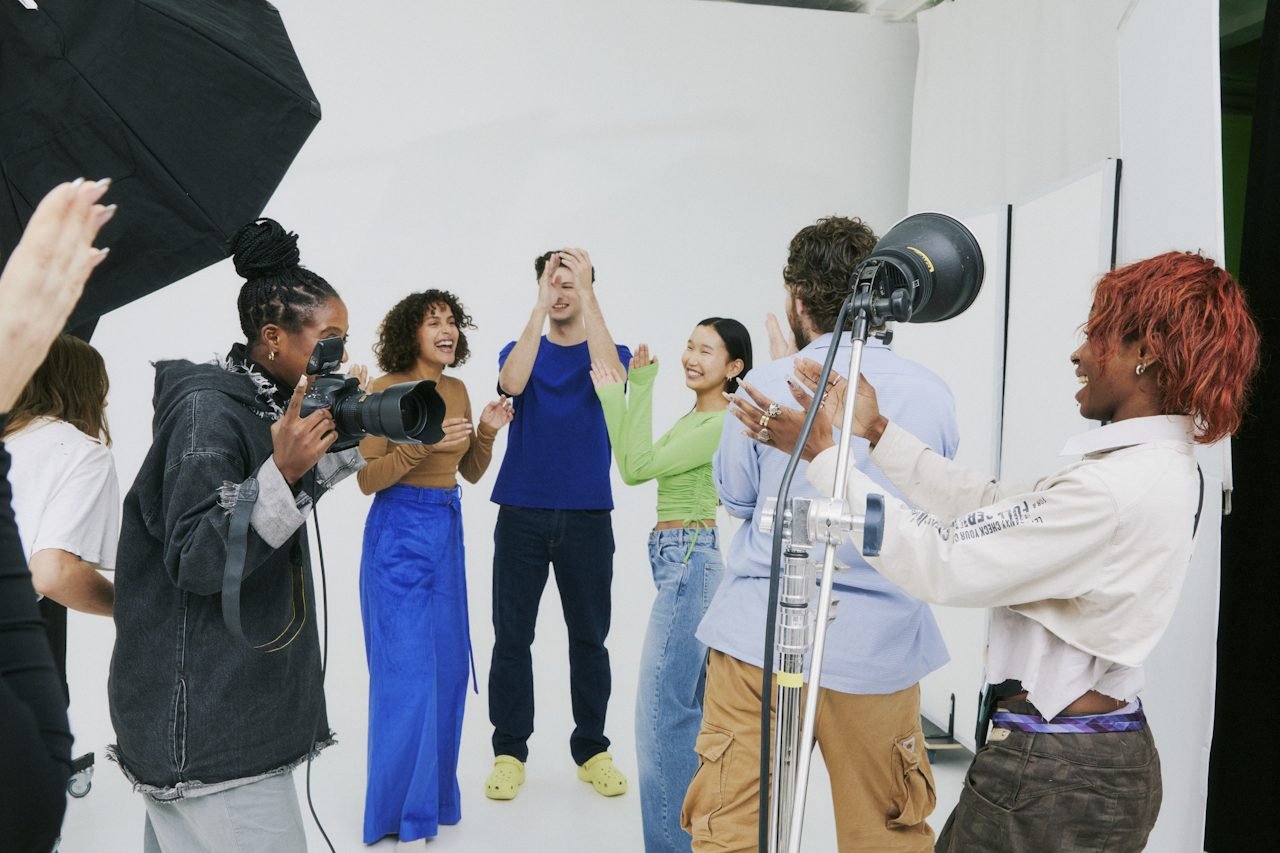 A diverse group of young people standing on in a photo studio having just finished a collaboration.