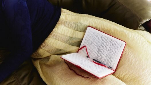 A person in a sweater and a skirt with a notebook in their lap