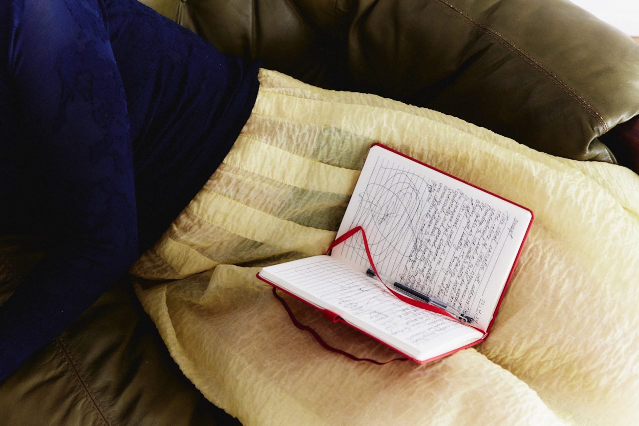 A person in a sweater and a skirt with a notebook in their lap