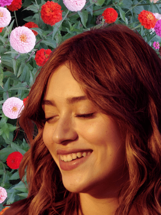 A young woman with the sun on her face and a collaged backdrop of flowers