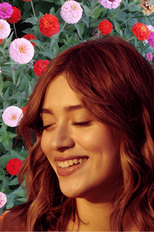 A young woman with the sun on her face and a collaged backdrop of flowers