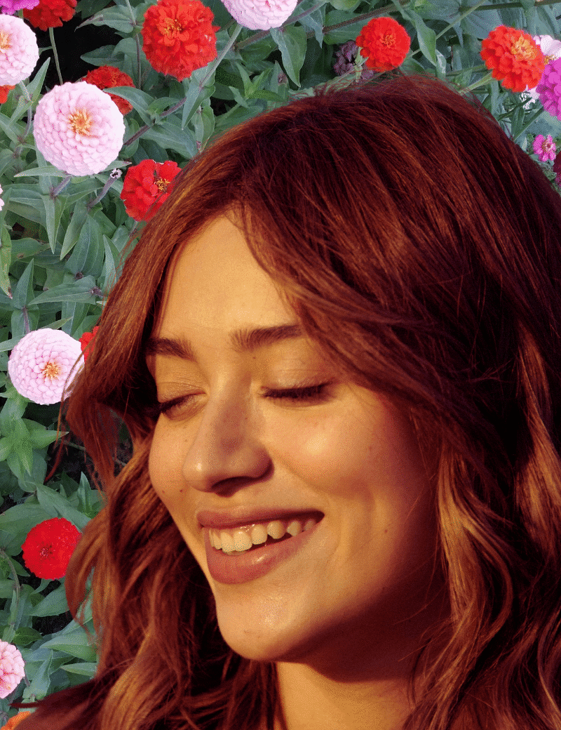 A young woman with the sun on her face and a collaged backdrop of flowers