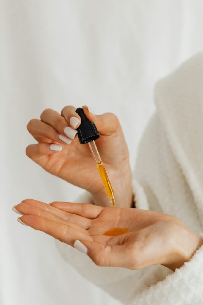 A woman dripping essential oils into her palm with an eye dropper.