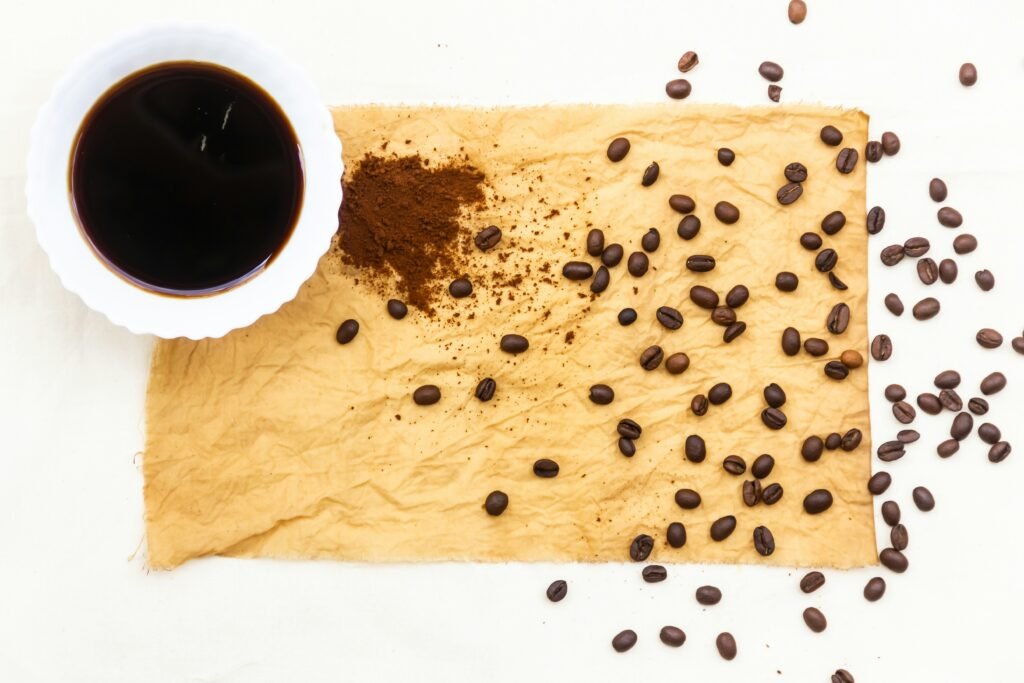 A fabric swatch dyed with coffee covered in coffee bean and a black up of coffee in the upper left corner.