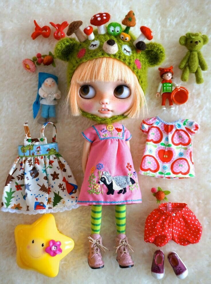A Blythe doll among a selection of different outfits.