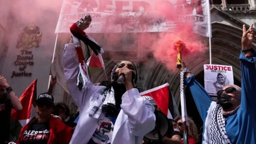 Pro-Palestinian protestors in a red smokey mist.
