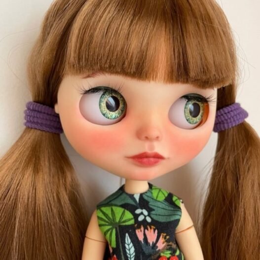 A custom OOAK Blythe doll with brunette hair in pig tails.