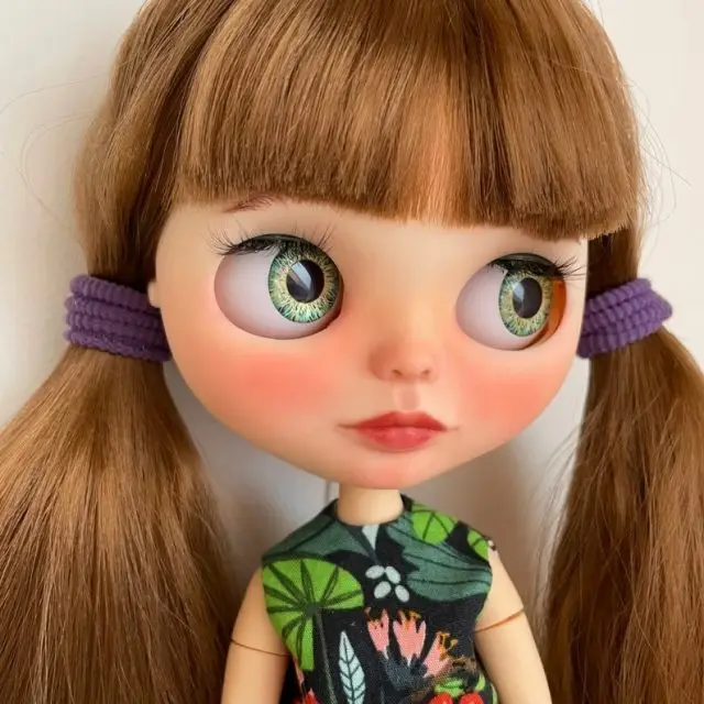 A custom OOAK Blythe doll with brunette hair in pig tails.