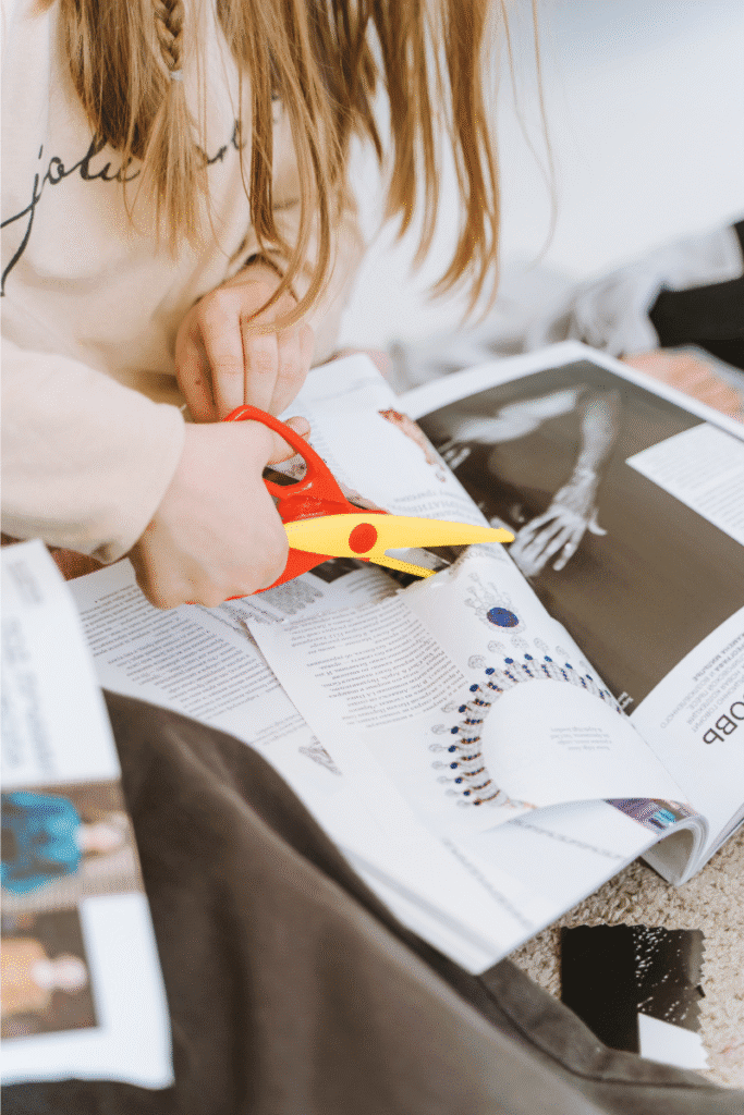 A woman cutting things out of a magazine using safety scissors