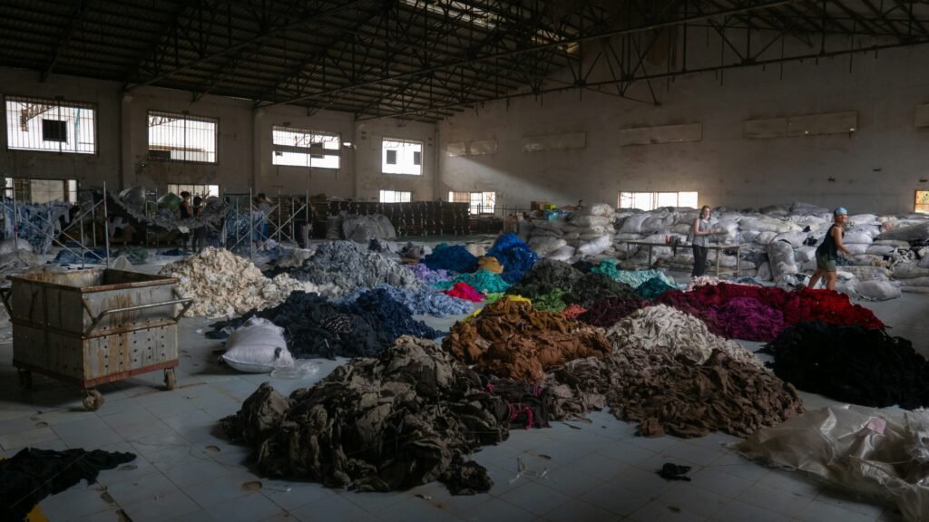 The interior of a warehouse where they are organization clothing and different fabrics by colour.
