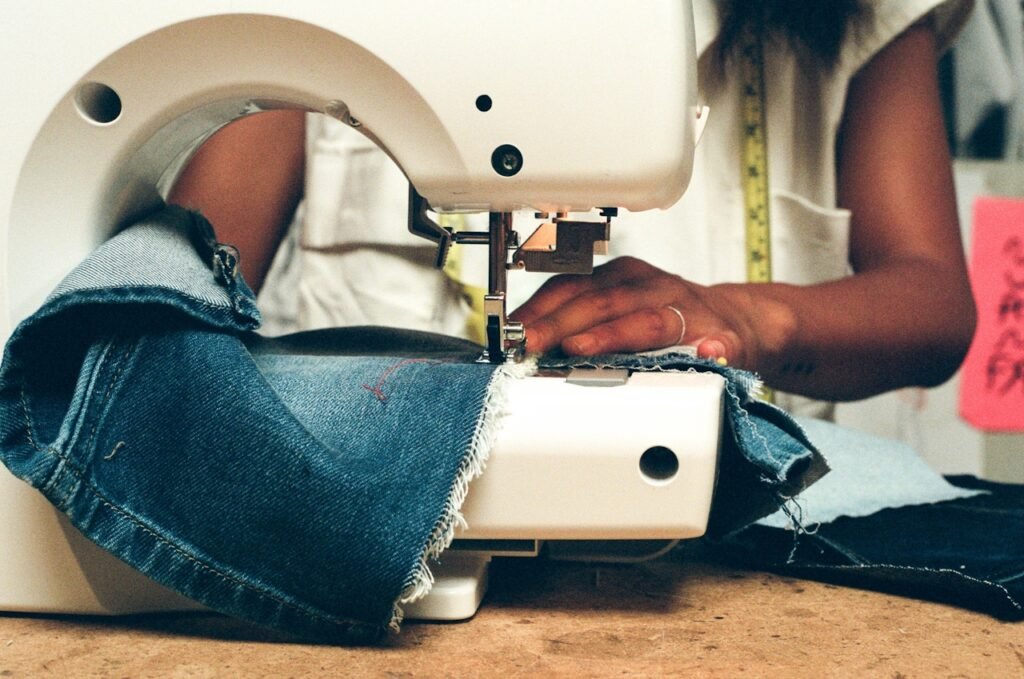 A person sewing denim on a sewing machine.