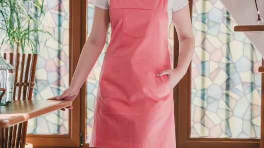 A redheaded woman wearing a pink utility apron