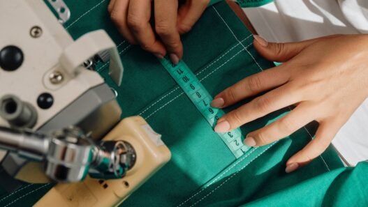 A person with a fabric measuring tape measuring a garment that they have in their sewing machine.