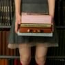 A women in a short skirt and knee high socks carrying a stack of books and standing in front of a bookcase.