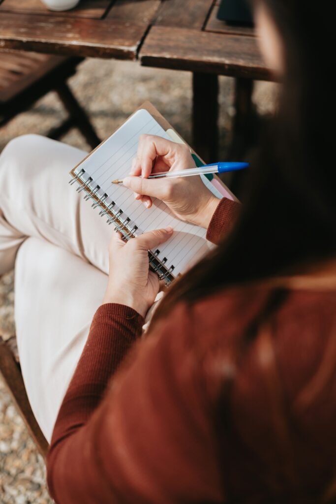 A person sits crosslegged with a pen and notebook in their lap.