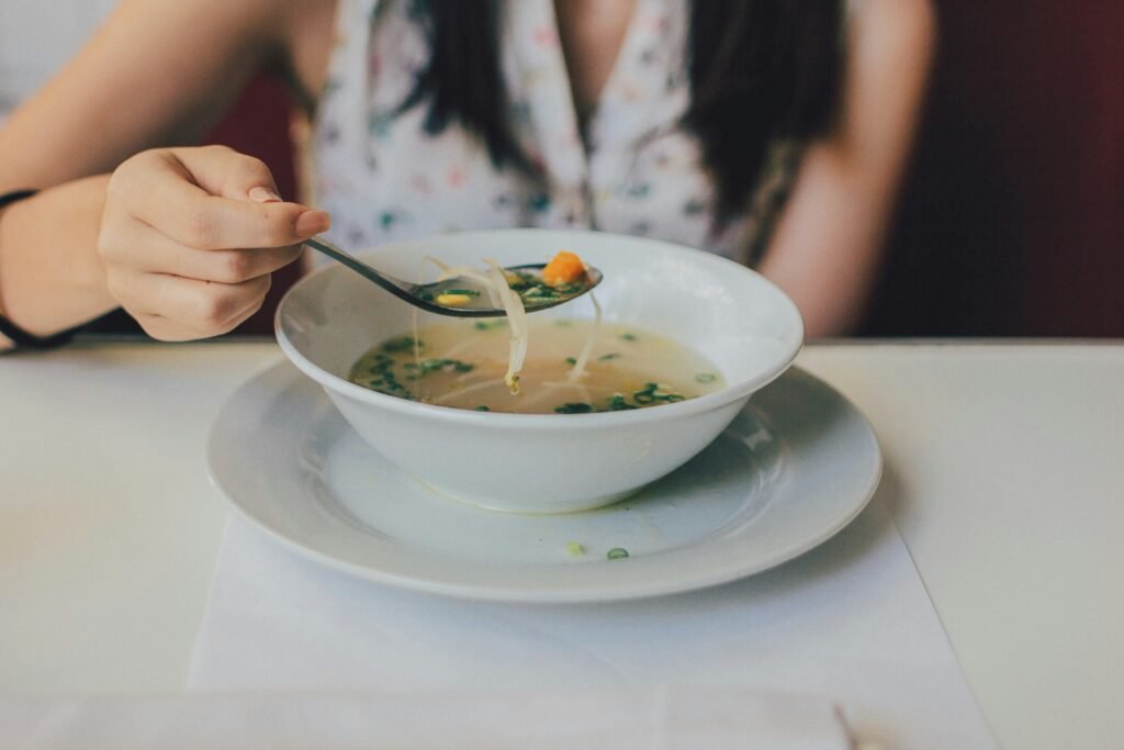 A woman eating a warm noodle soup.