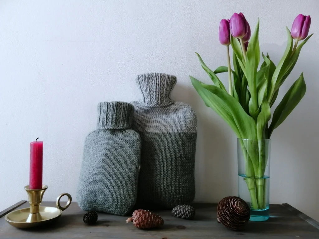 Two grey hand knit water bottle covers