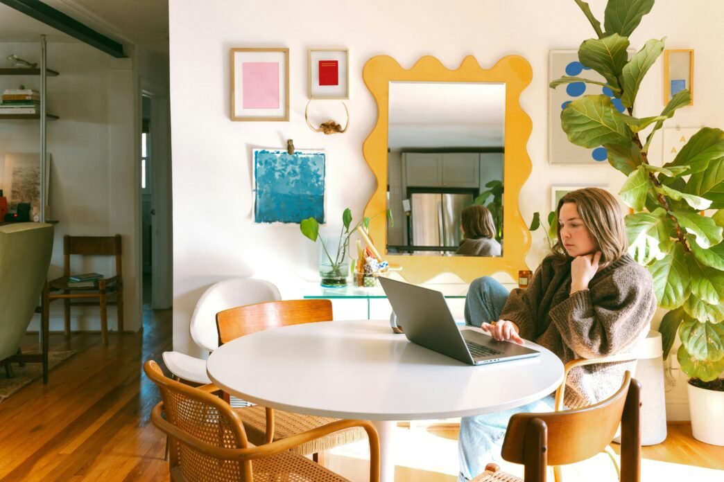 A woman sitting at her computer in a brightly decorated room,