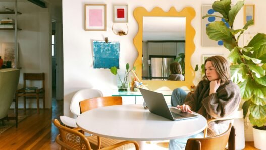 A woman sitting at her computer in a brightly decorated room,