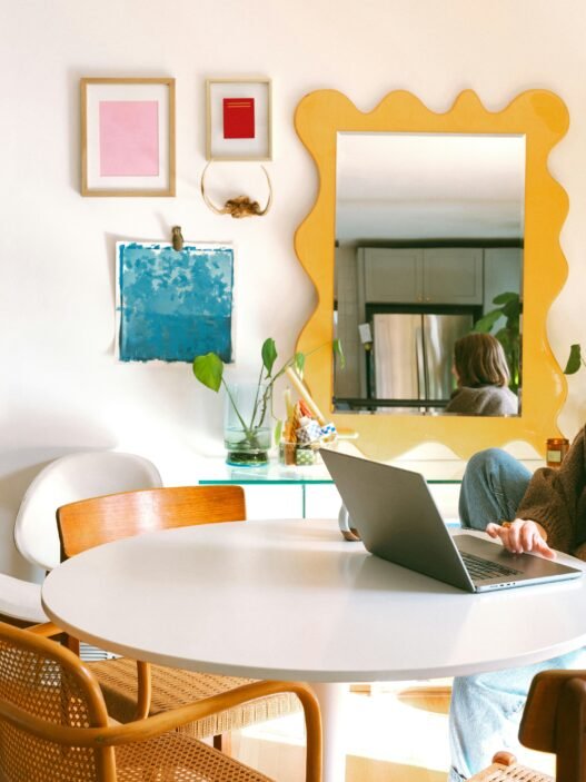 A woman sitting at her computer in a brightly decorated room,