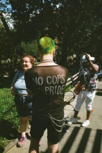 A punk with the writing 'No Cops at Pride' on the back of their shirt.